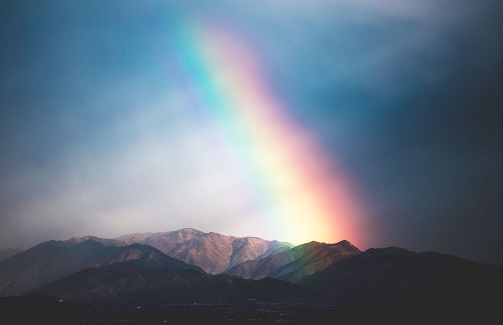 a rainbow of full spectrum light over mountain range